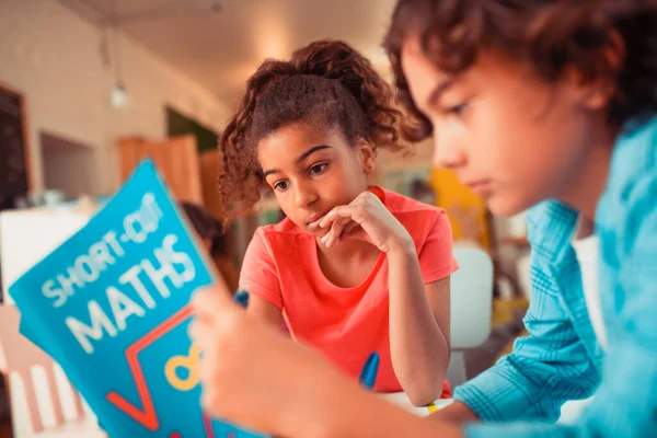 Två intresserade skolbarn läser en matematisk lärobok — Stockfoto