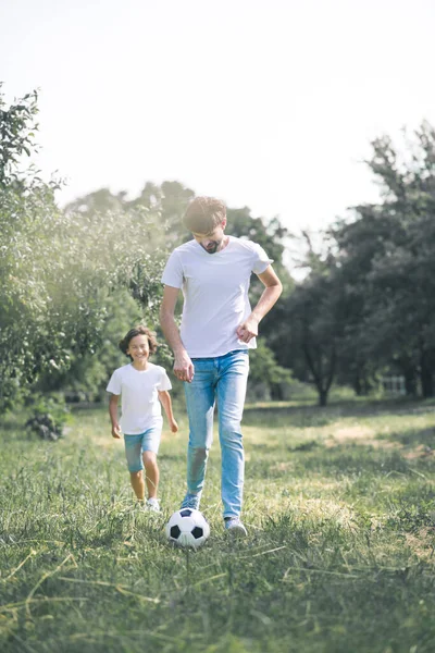 Ragazzo dai capelli scuri e suo padre che giocano con la palla in giardino — Foto Stock