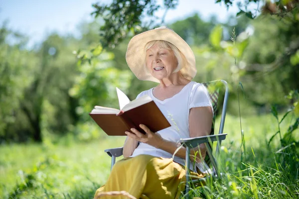 Mujer leyendo un libro sentado en una tumbona —  Fotos de Stock