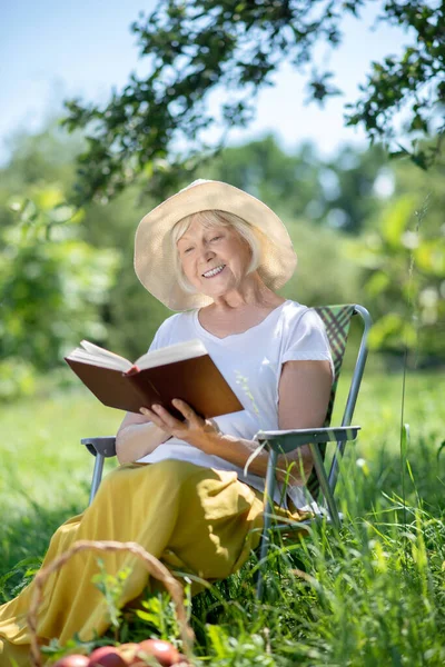 Femme lisant un livre intéressant dans son jardin — Photo