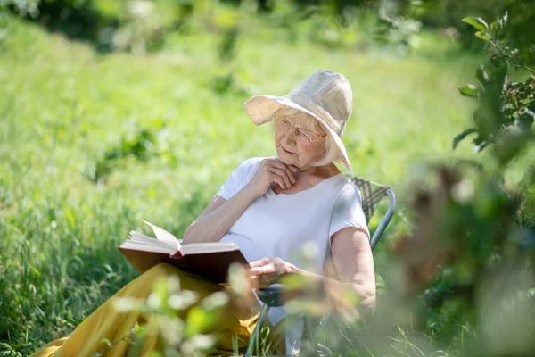 Ontspannen oudere vrouw die een boek buiten leest — Stockfoto