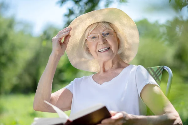 Vreugdevolle vrouw die een boek leest in de tuin — Stockfoto