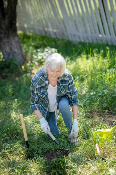 Mulher ativa trabalhando com um ancinho em seu jardim — Fotografia de Stock