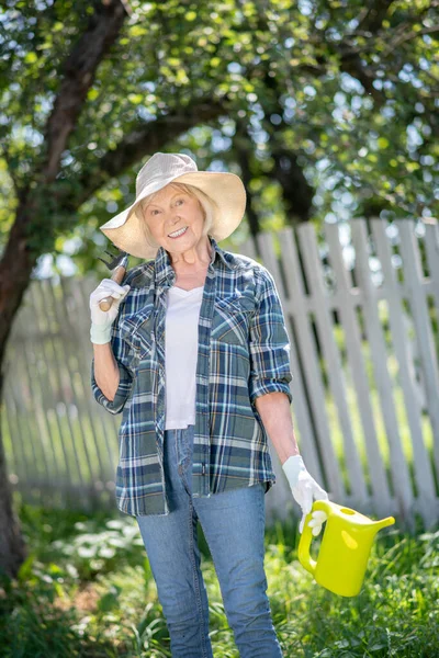 Glada kvinna vattna växter i sin grönsaksland — Stockfoto