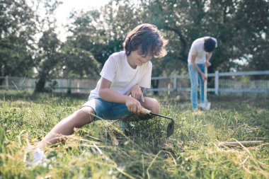Koyu saçlı çocuk ve babası bahçe işleriyle meşgul görünüyorlar.