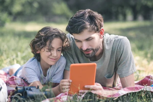 Ο μπαμπάς και ο γιος βλέποντας κάτι στο tablet και αναζητούν εμπλέκονται — Φωτογραφία Αρχείου