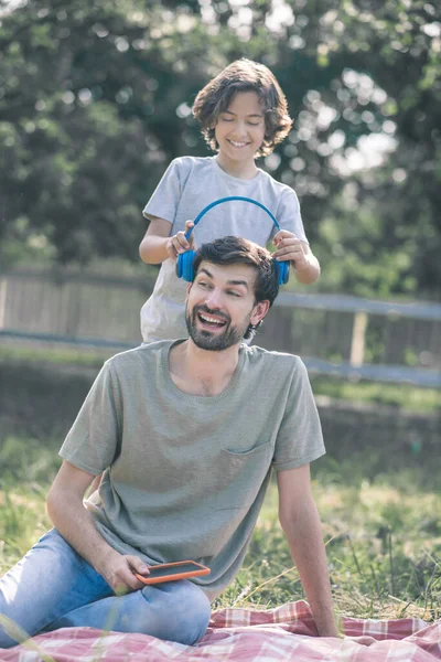 Le son sätta hörlurar på hans pappor huvud, båda mår bra — Stockfoto