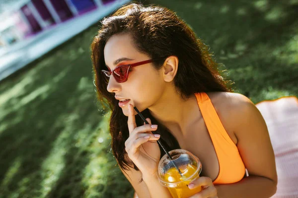 Menina morena bonito segurando um copo com suco e olhando pensativo — Fotografia de Stock