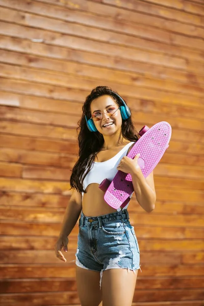 Όμορφη μελαχρινή κοπέλα με skateboard αίσθημα ισχυρή — Φωτογραφία Αρχείου