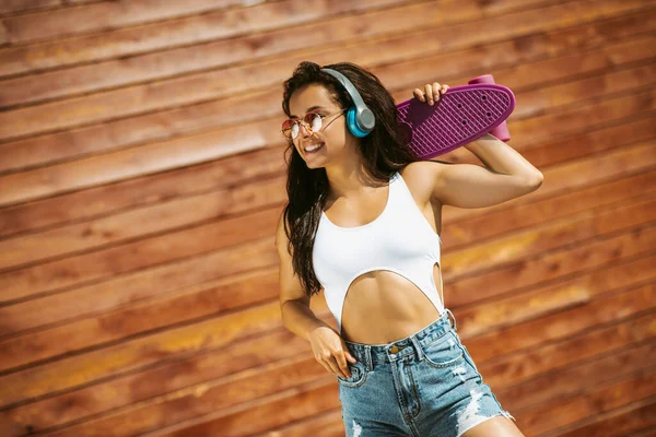 Krásná brunetka dívka s skateboard pocit úžasný — Stock fotografie