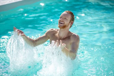 Havuzda beline kadar suya batmış bir adam.