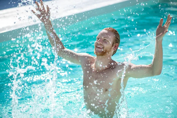Homem sorridente na água da piscina com as mãos para cima — Fotografia de Stock
