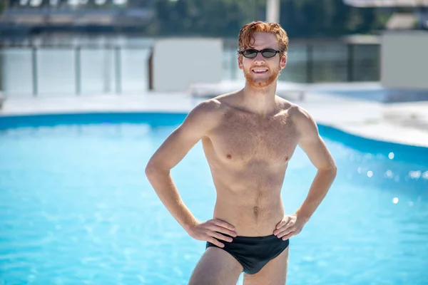 Havuzun yanında duran güneş gözlüklü kızıl saçlı adam. — Stok fotoğraf