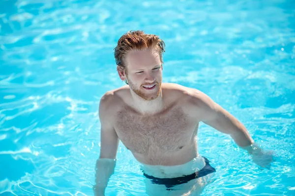 Roodharige jonge man die in het water loopt. — Stockfoto