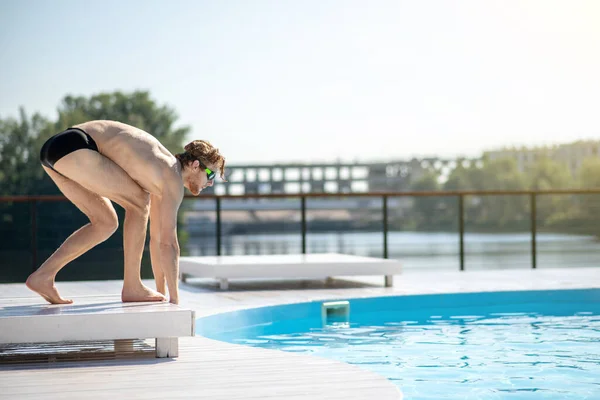 Homme en lunettes de natation penché sur le bord de la piscine — Photo