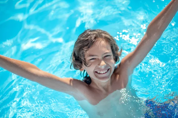 Smiling boy in water on shoulders with hands up — Stock Photo, Image