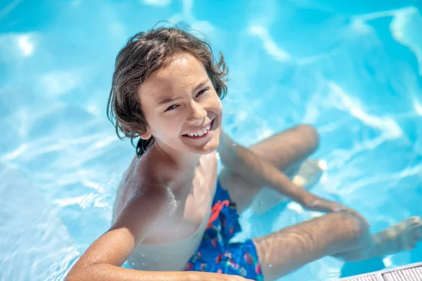 Junge sitzt im Wasser im Pool — Stockfoto