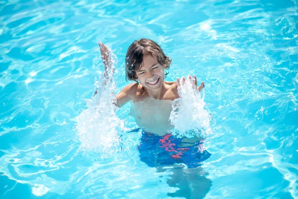 Boy standing in water raising his hands up — Stock Photo, Image