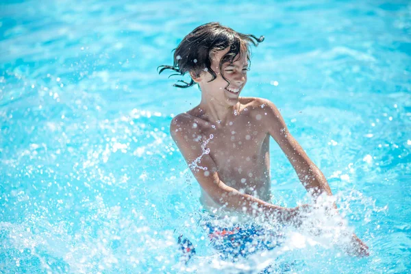 Energetischer Junge steht im Wasser und macht Spritzer — Stockfoto