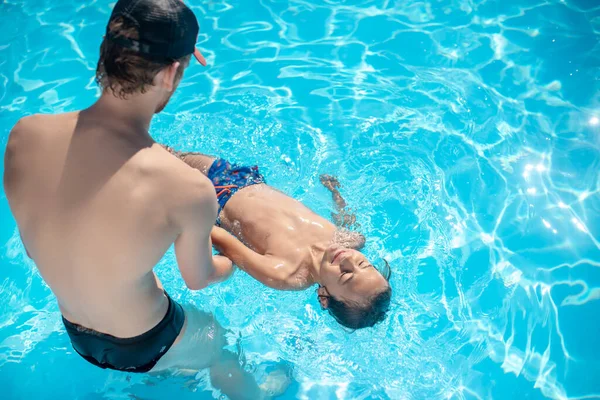 Homem apoiando as costas do menino deitado na água — Fotografia de Stock