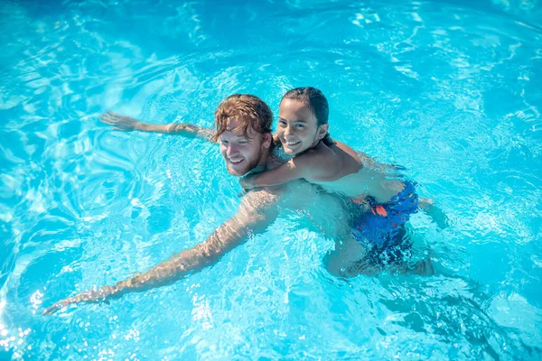 Pai com filho de costas nadando na piscina — Fotografia de Stock
