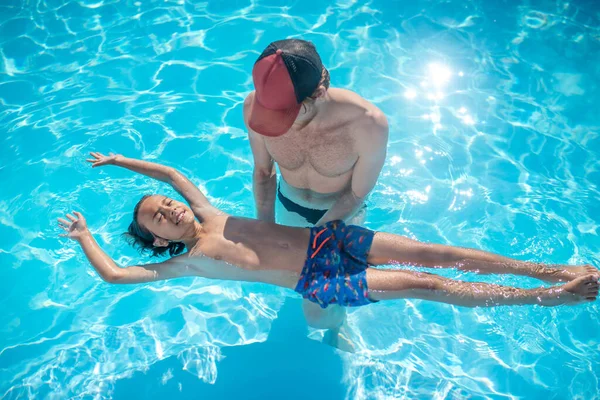 Instrutor de apoio menino deitado de costas na água — Fotografia de Stock