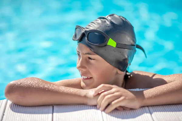 Boy in swimming cap resting his hands on poolside — Stock Photo, Image