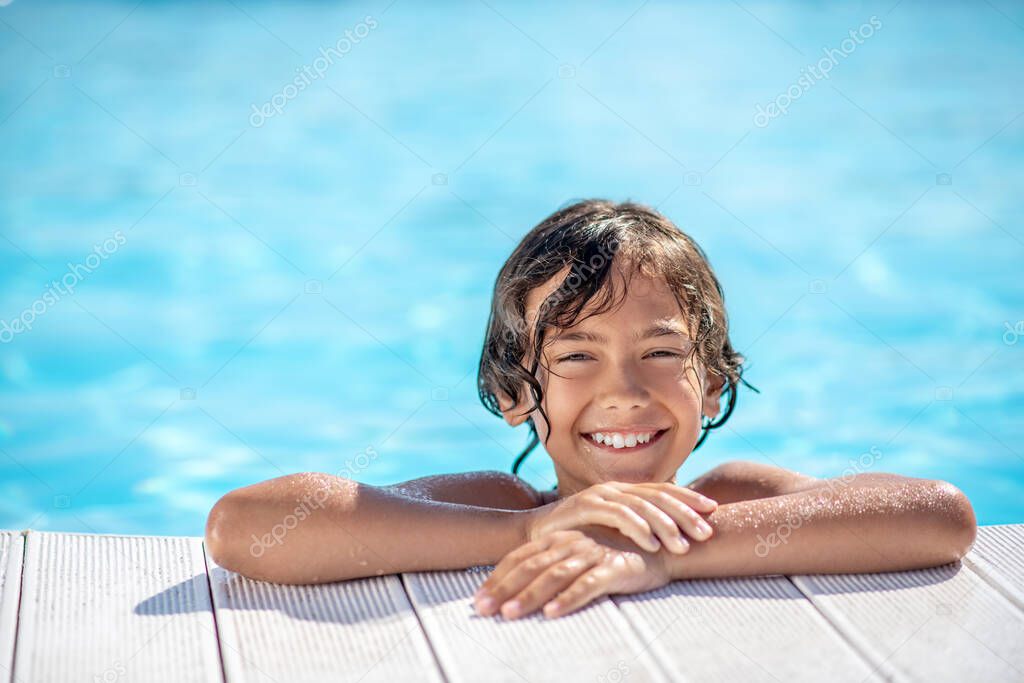 Happy boys face peeking out of the pool