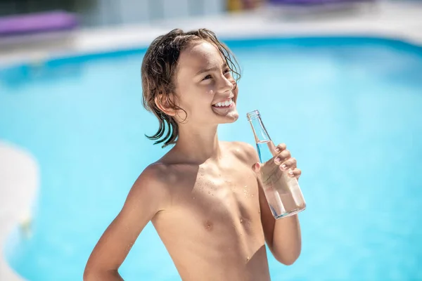 Rapaz feliz com garrafa de água por piscina — Fotografia de Stock