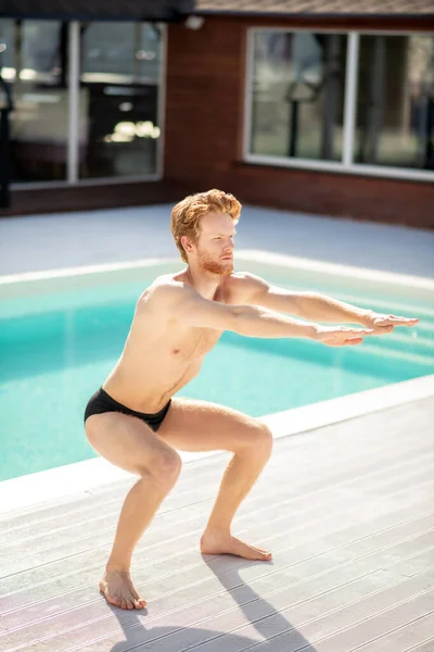 Jovem atraente fazendo esportes perto da piscina — Fotografia de Stock