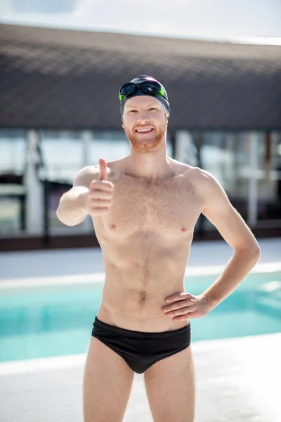 Smiling man in swimsuit showing hand all perfectly — Stock Photo, Image