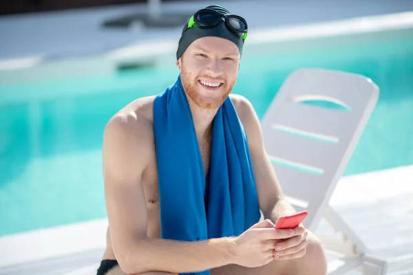 Homem feliz na touca de natação na cama de sol pela piscina — Fotografia de Stock