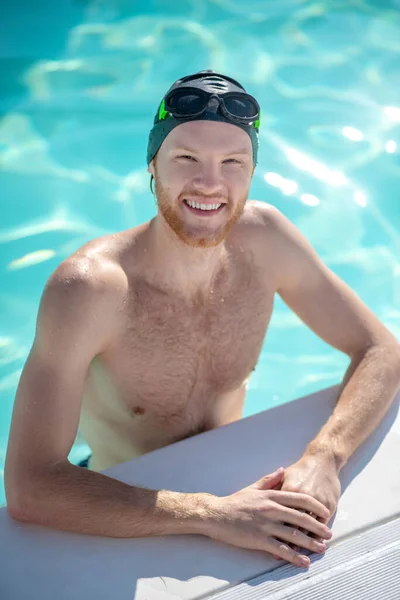 Nadador sorridente em pé na água na borda da piscina — Fotografia de Stock