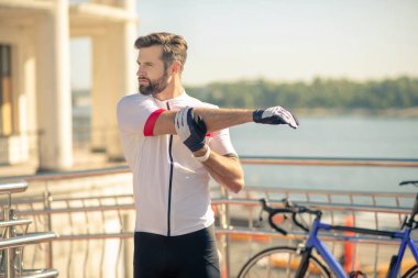 Eldivenli genç adam ellerini ısıtıyor.