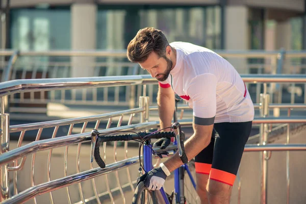 Внимательный велогонщик осматривает плоское велосипедное колесо — стоковое фото