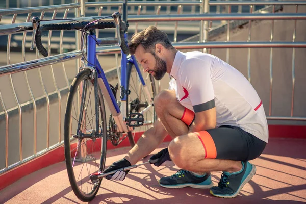 Man with pump crouched near bicycle wheel