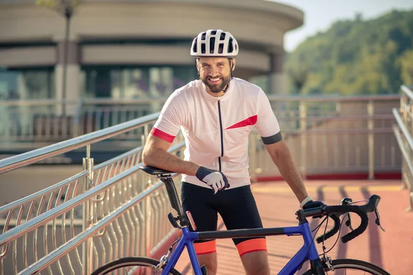 Велосипедист с белозубой улыбкой, стоящий с велосипедом — стоковое фото