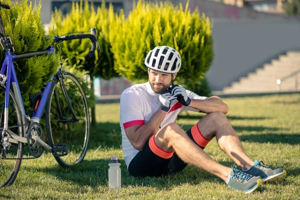 Уставший велосипедист отдыхает на траве под солнцем — стоковое фото