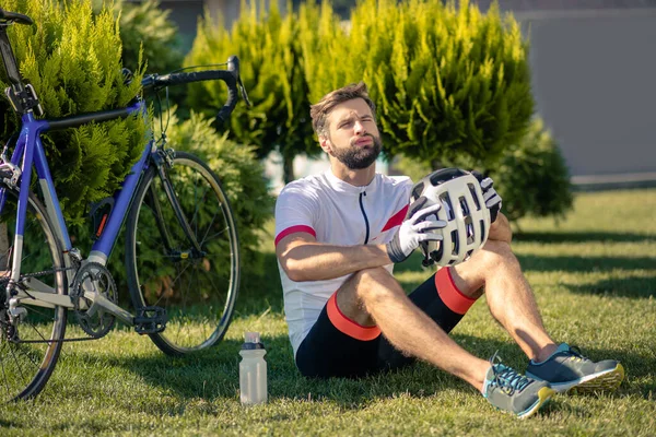 Уставший мужчина отдыхает на траве возле велосипеда — стоковое фото