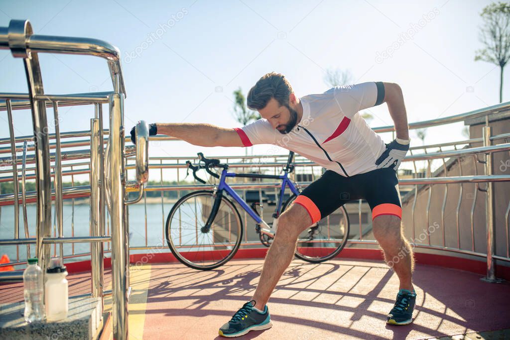 Man in sportswear squatting near handrails outdoors