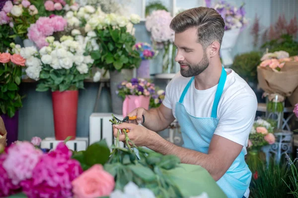 Envolvido florista barbudo flores de corte dentro da loja de flores — Fotografia de Stock