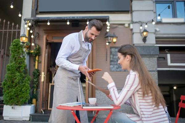 Mujer morena sentada en cafetería abierta, menú de celebración, consultoría con camarero — Foto de Stock