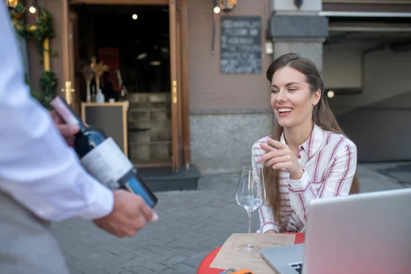 Skäggig servitör visar flaska rött vin, kvinnlig kund gör sitt val — Stockfoto