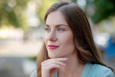 Çekici kahverengi saçlı kadın çenesini dinlendiriyor.