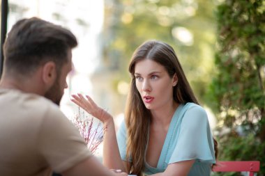 Üzgün çift açık hava kafesinde oturmuş birbirleriyle tartışıyorlar.