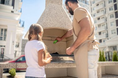 Güzel kız babasını ızgara yaparken izliyor.