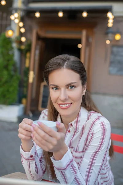 Leende kvinna som håller kaffekopp i uteservering, leende — Stockfoto