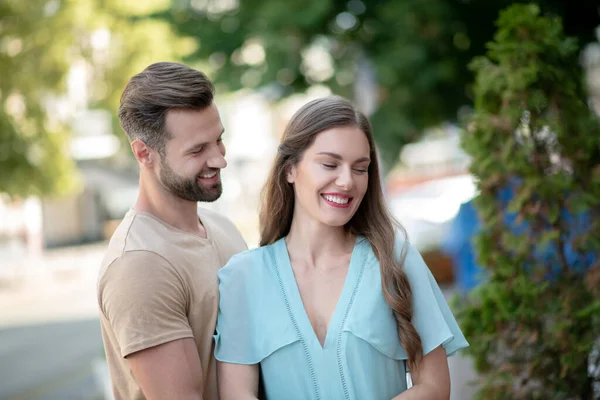 Baard man knuffelen teder glimlachen vrouw in blauw jurk — Stockfoto