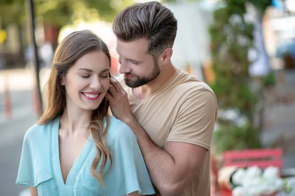 Bearded male standing beside female in blue dress, stroking her hair — Stock Photo, Image