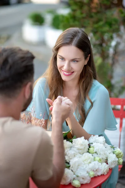 Skägg hane och hona i blå klänning sittande vid rött bord, hålla händer — Stockfoto